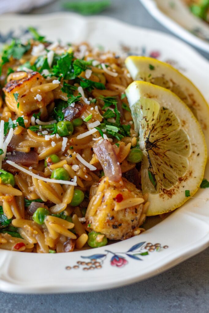 A plate of creamy lemon pepper tofu and orzo topped with vegan parmesan and parsley.