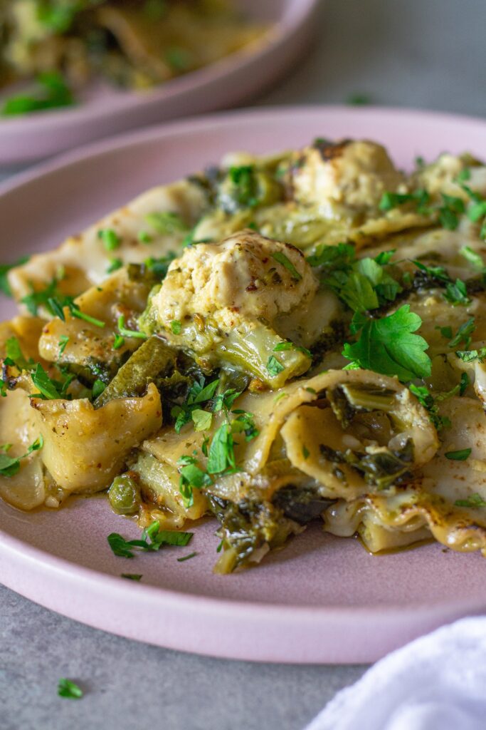 Finished lasagna topped with melty mozzarella, dollops of tofu ricotta, and fresh parsley