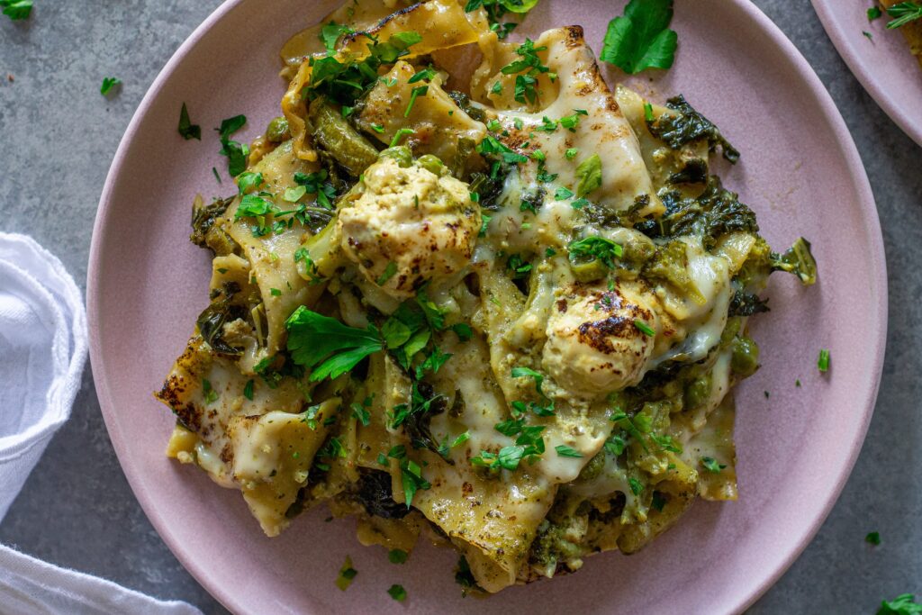 Finished lasagna topped with melty mozzarella, dollops of tofu ricotta, and fresh parsley