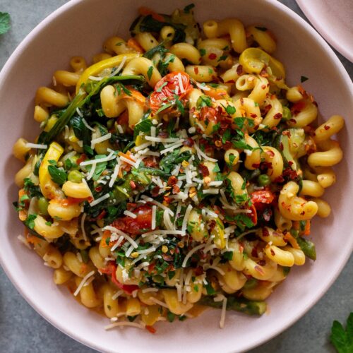 Close-up of creamy vegan pasta primavera with asparagus, peas, and cherry tomatoes