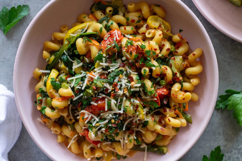 Close-up of creamy vegan pasta primavera with asparagus, peas, and cherry tomatoes