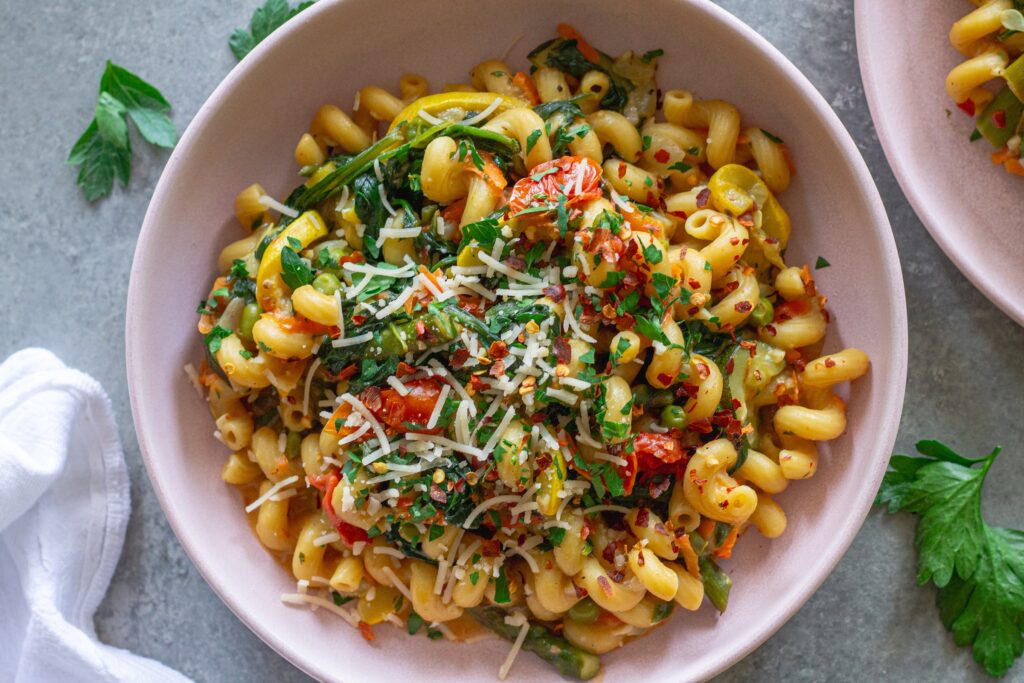 Close-up of creamy vegan pasta primavera with asparagus, peas, and cherry tomatoes
