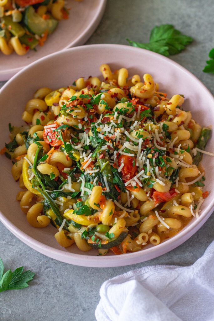 Close-up of creamy vegan pasta primavera with asparagus, peas, and cherry tomatoes