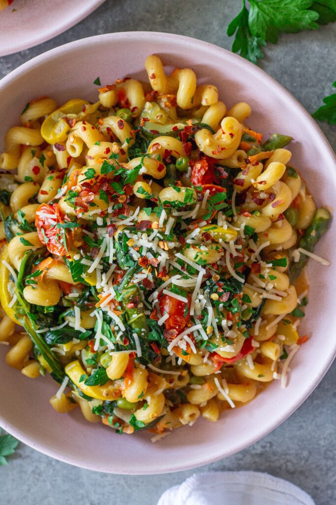 Close-up of creamy vegan pasta primavera with asparagus, peas, and cherry tomatoes