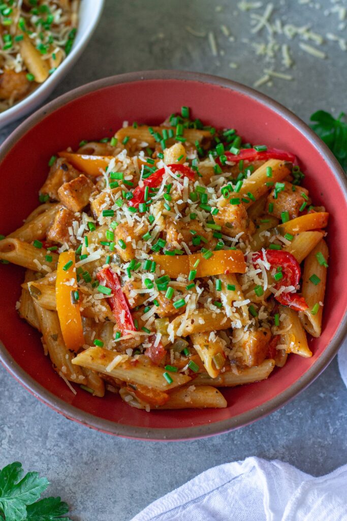 Bowl of Creamy One Pan Cajun-Inspired Pasta topped with chives and extra vegan parmesan.