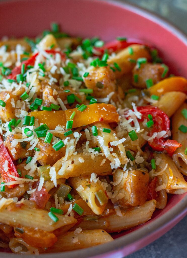 Bowl of Creamy One Pan Cajun-Inspired Pasta topped with chives and extra vegan parmesan.