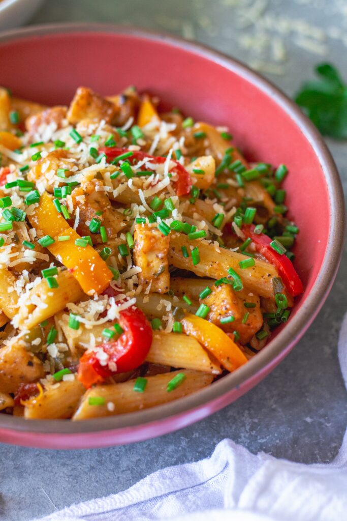 Bowl of Creamy One Pan Cajun-Inspired Pasta topped with chives and extra vegan parmesan.