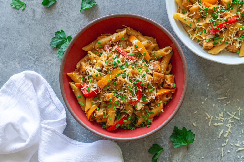 Serving of Creamy One Pan Cajun-Inspired Pasta topped with chives and extra vegan parmesan.