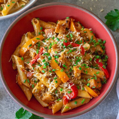 Bowl of Creamy One Pan Cajun-Inspired Pasta topped with chives and extra vegan parmesan.