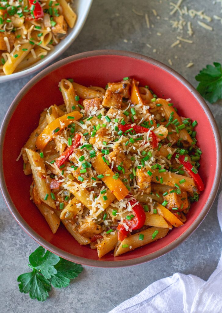 Bowl of Creamy One Pan Cajun-Inspired Pasta topped with chives and extra vegan parmesan.
