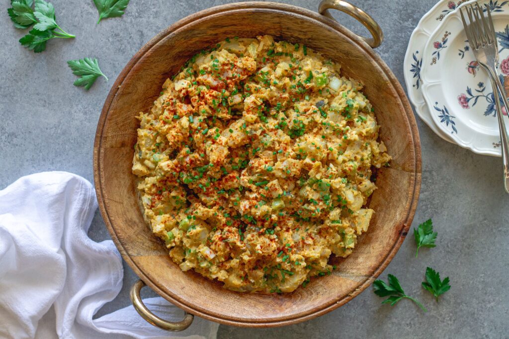 Overhead shot of creamy vegan Southern-style potato salad in serving bowl garnished with smoked paprika and chives