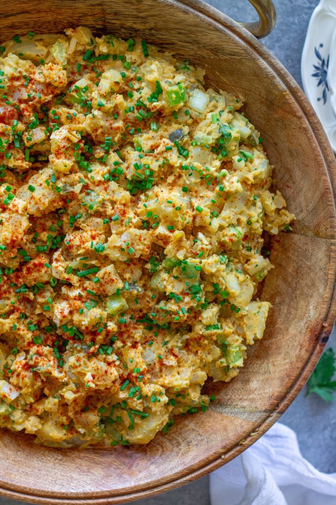 Overhead shot of creamy vegan Southern-style potato salad in serving bowl garnished with smoked paprika and chives