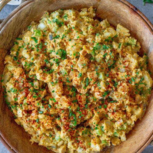 Overhead shot of creamy vegan Southern-style potato salad in serving bowl garnished with smoked paprika and chives