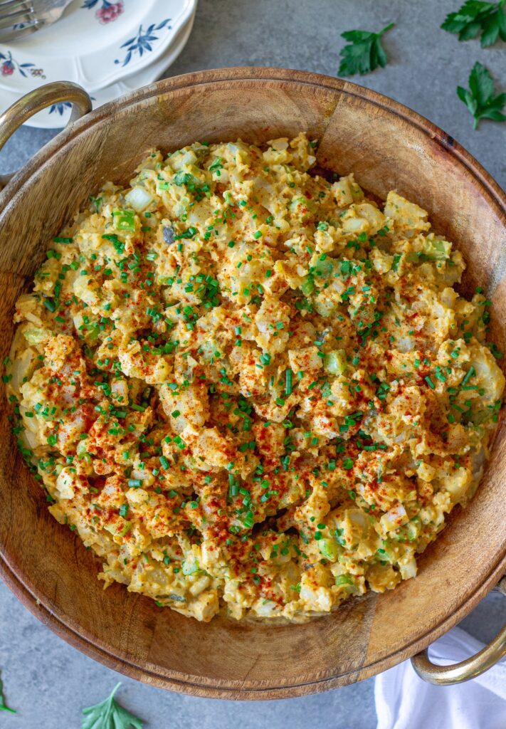Overhead shot of creamy vegan Southern-style potato salad in serving bowl garnished with smoked paprika and chives