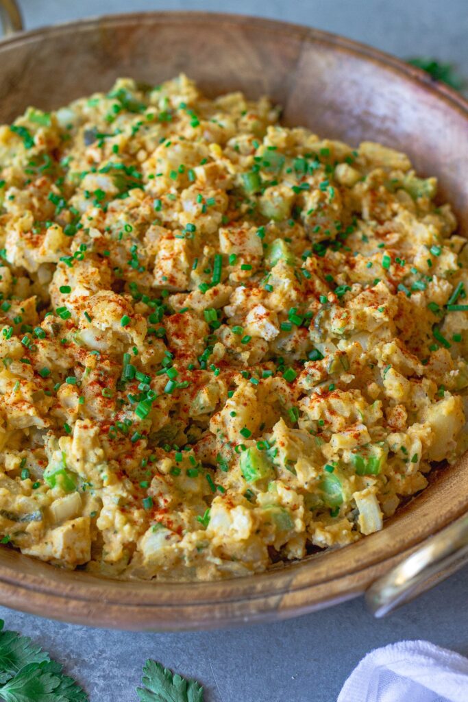 Overhead shot of creamy vegan Southern-style potato salad in serving bowl garnished with smoked paprika and chives