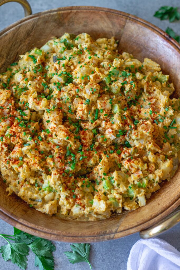Overhead shot of creamy vegan Southern-style potato salad in serving bowl garnished with smoked paprika and chives