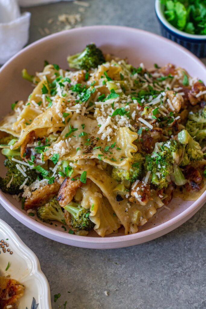 Overhead shot of creamy chicken and broccoli skillet lasagna on a plate, garnished with fresh parsley and vegan parmesan.