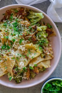 Overhead shot of creamy chicken and broccoli skillet lasagna on a plate, garnished with fresh parsley and vegan parmesan.