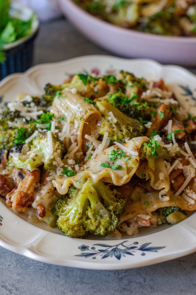 Overhead shot of creamy chicken and broccoli skillet lasagna on a plate, garnished with fresh parsley and vegan parmesan.