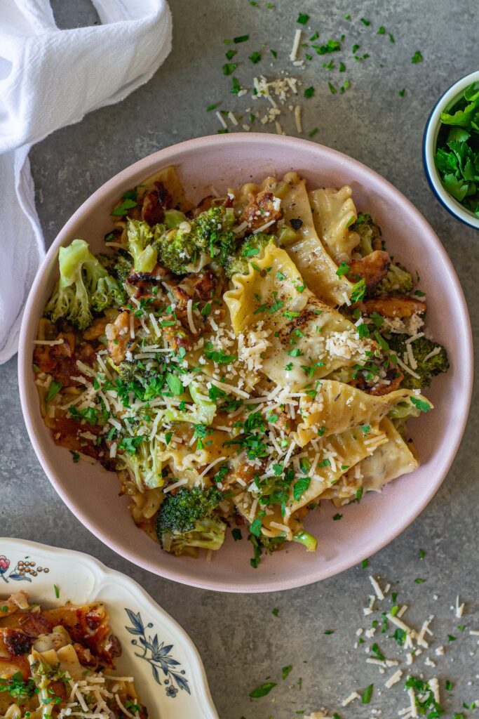 Overhead shot of creamy chicken and broccoli skillet lasagna on a plate, garnished with fresh parsley and vegan parmesan.