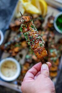 Close up image of garlic parmesan tofu skewer brushed with garlic parmesan butter and garnished with parsley, red chili flakes, and grated parmesan.