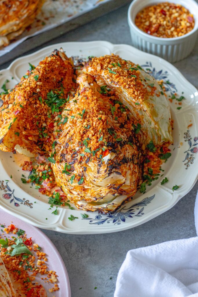 Grilled cabbage wedges topped with Calabrian chili lemon aioli, crispy golden breadcrumbs, and fresh minced parsley on a serving platter.