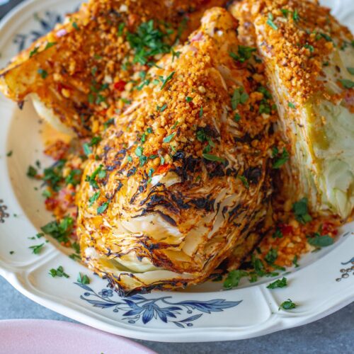 Grilled cabbage wedges topped with Calabrian chili lemon aioli, crispy golden breadcrumbs, and fresh minced parsley on a serving platter.
