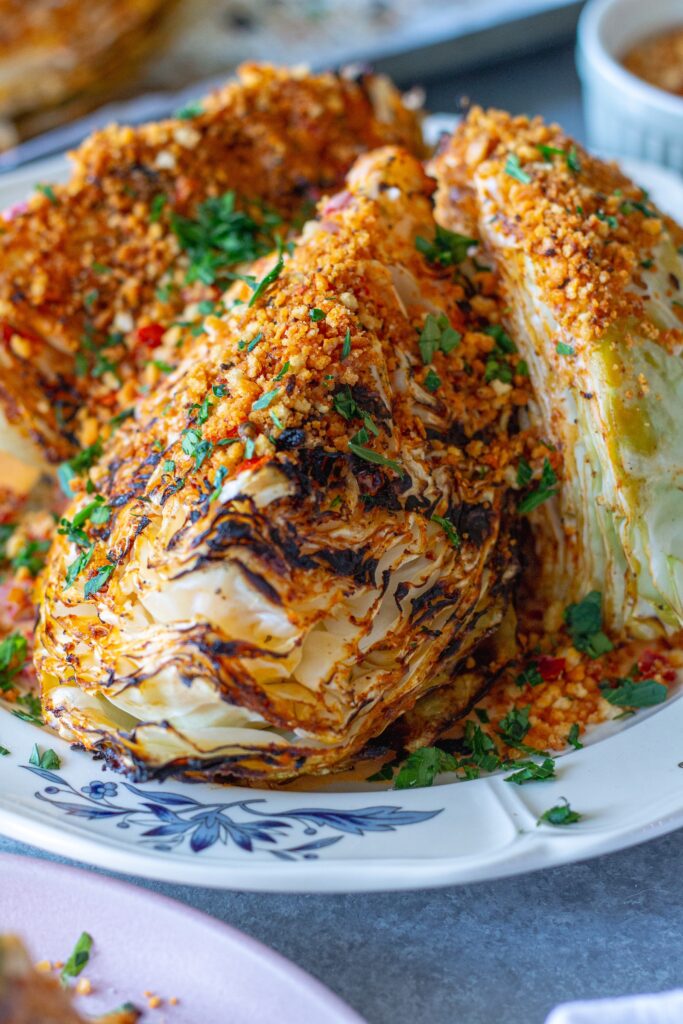 Grilled cabbage wedges topped with Calabrian chili lemon aioli, crispy golden breadcrumbs, and fresh minced parsley on a serving platter.