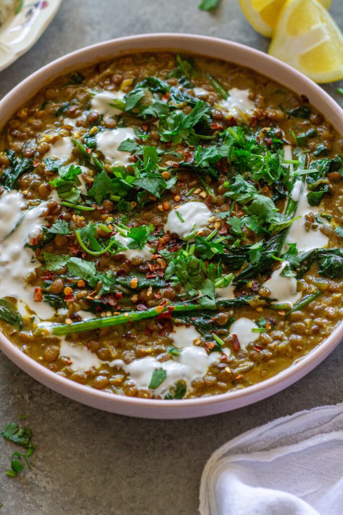Shot of one pan coconut lentil curry garnished with coconut cream and cilantro, and served with a side of rice.