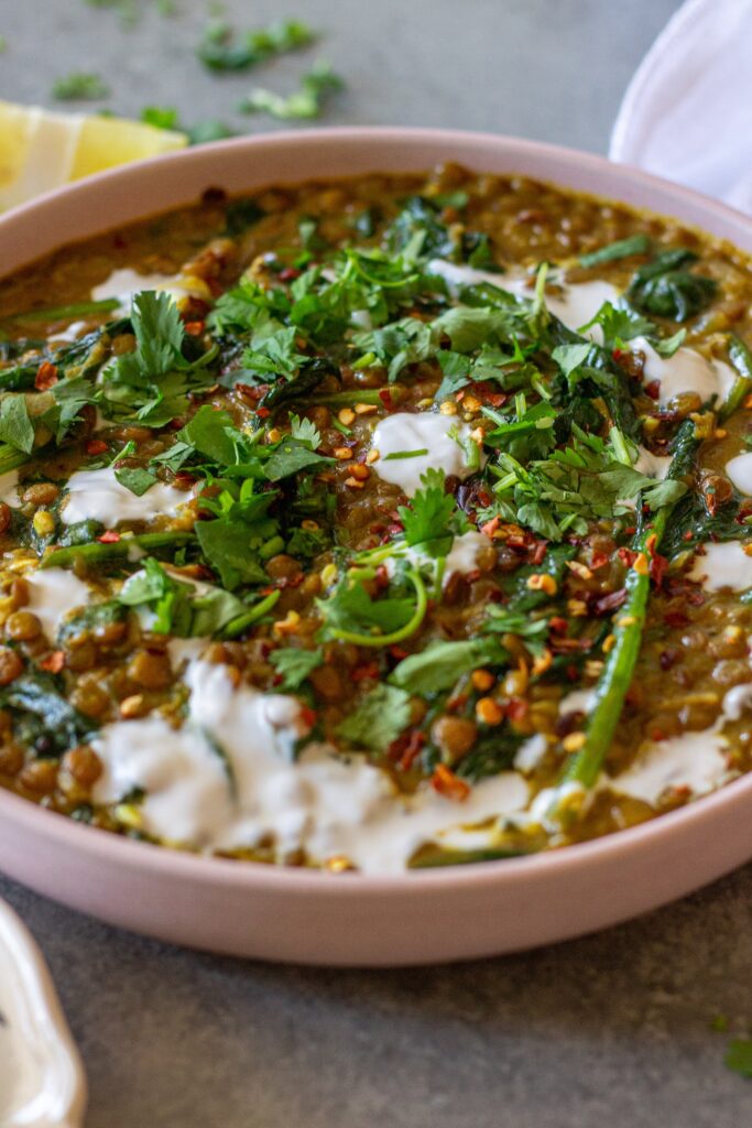 Shot of one pan coconut lentil curry garnished with coconut cream and cilantro, and served with a side of rice.