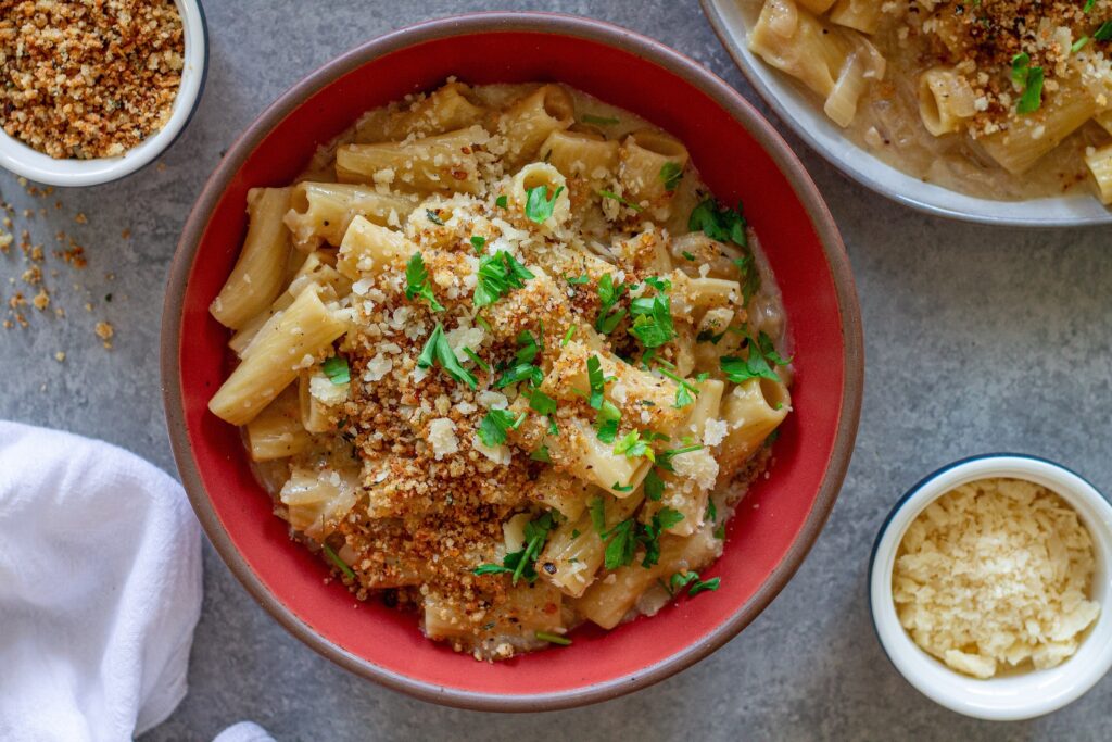 Overhead shot of creamy one pot French onion pasta garnished with crispy breadcrumbs, vegan parmesan, and parsley.