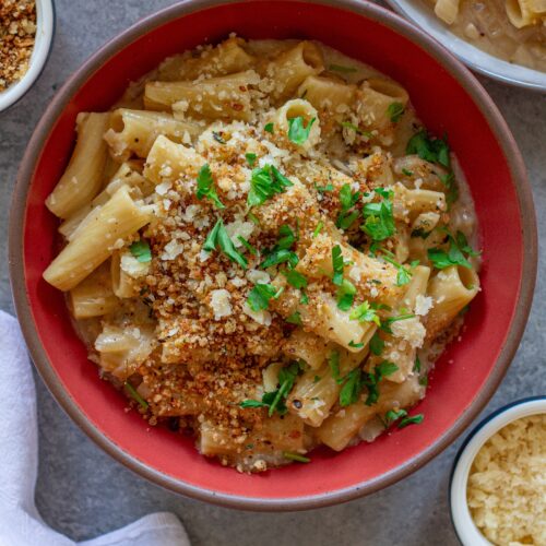 Overhead shot of creamy one pot French onion pasta garnished with crispy breadcrumbs, vegan parmesan, and parsley.