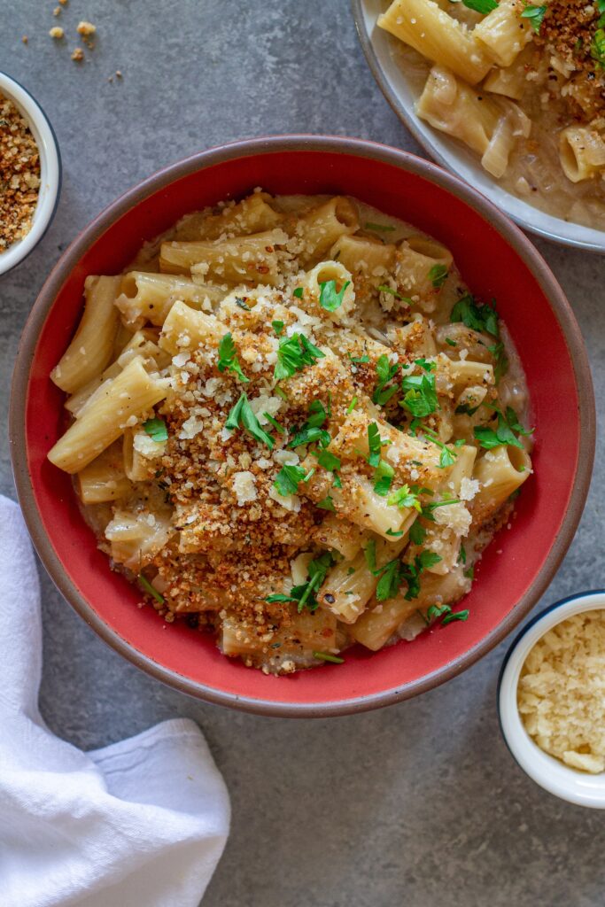Overhead shot of creamy one pot French onion pasta garnished with crispy breadcrumbs, vegan parmesan, and parsley.