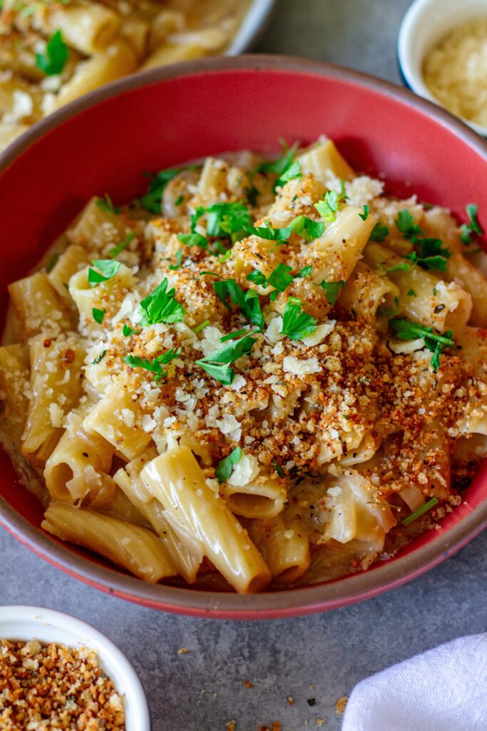Overhead shot of creamy one pot French onion pasta garnished with crispy breadcrumbs, vegan parmesan, and parsley.