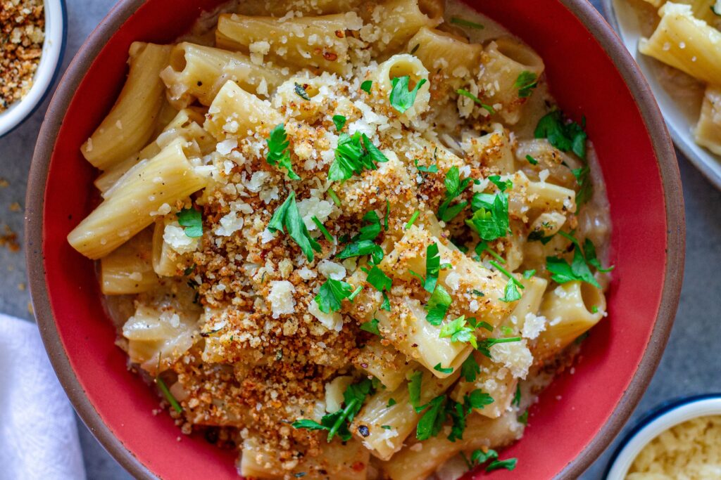 Overhead shot of creamy one pot French onion pasta garnished with crispy breadcrumbs, vegan parmesan, and parsley.