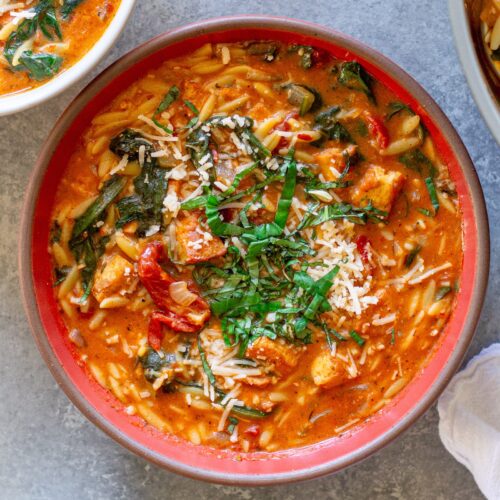 creamy bowl of Vegan Marry Me “Chicken” and Orzo Soup with crispy tofu, spinach, and garnished with parmesan and basil.