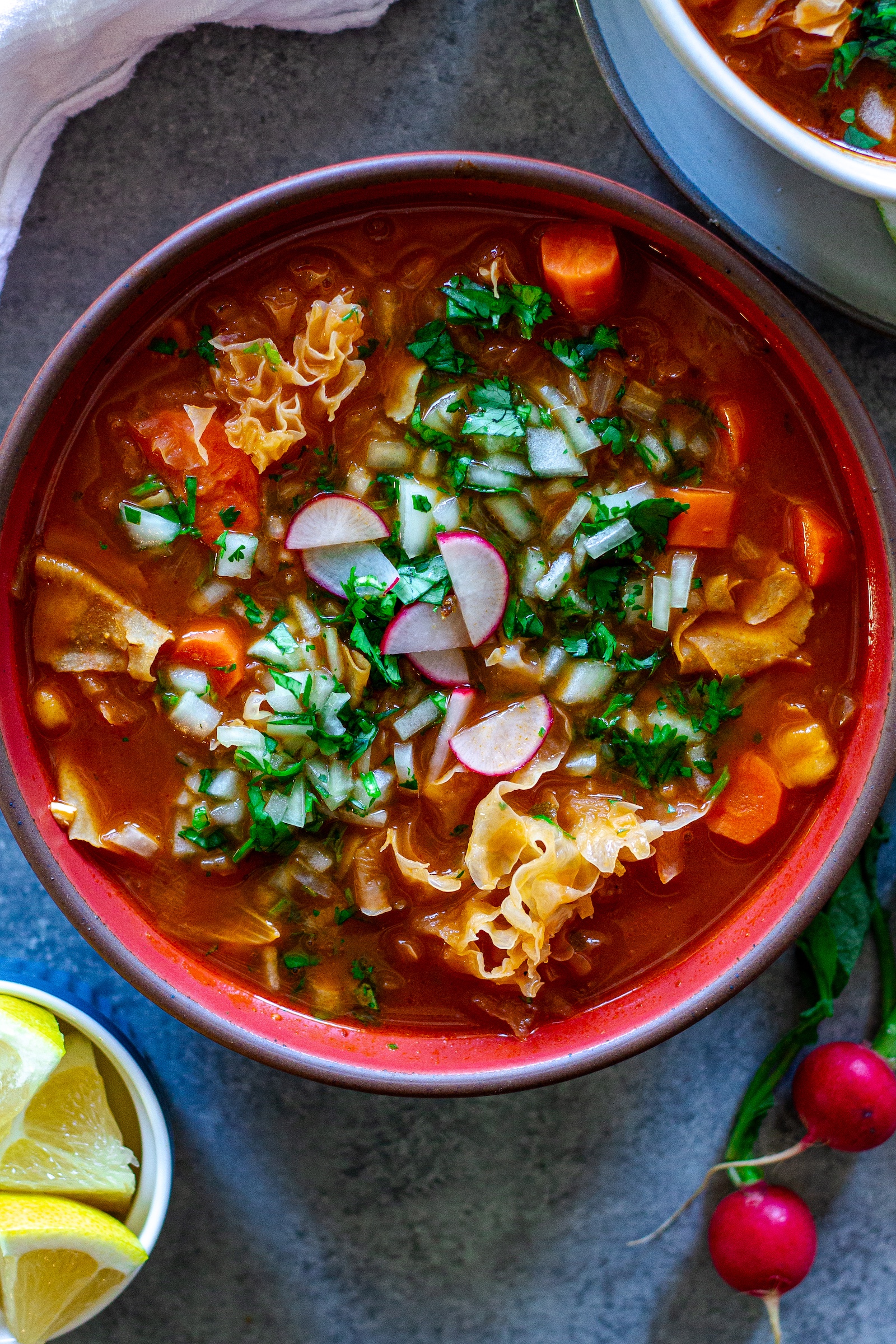 Bowl of vegan menudo with snow mushrooms, hominy, and red chile broth