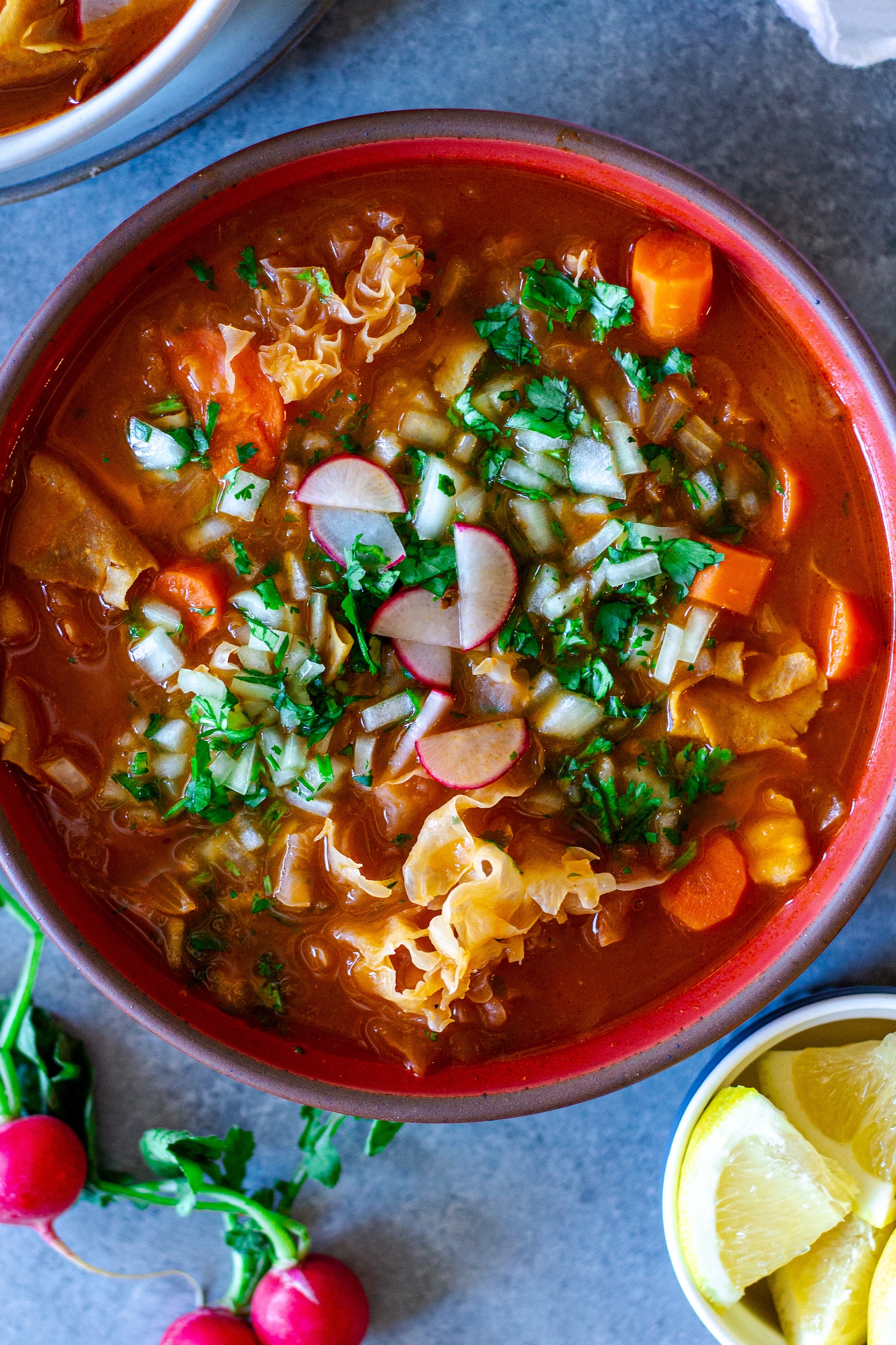 Bowl of vegan menudo with snow mushrooms, hominy, and red Chile broth.