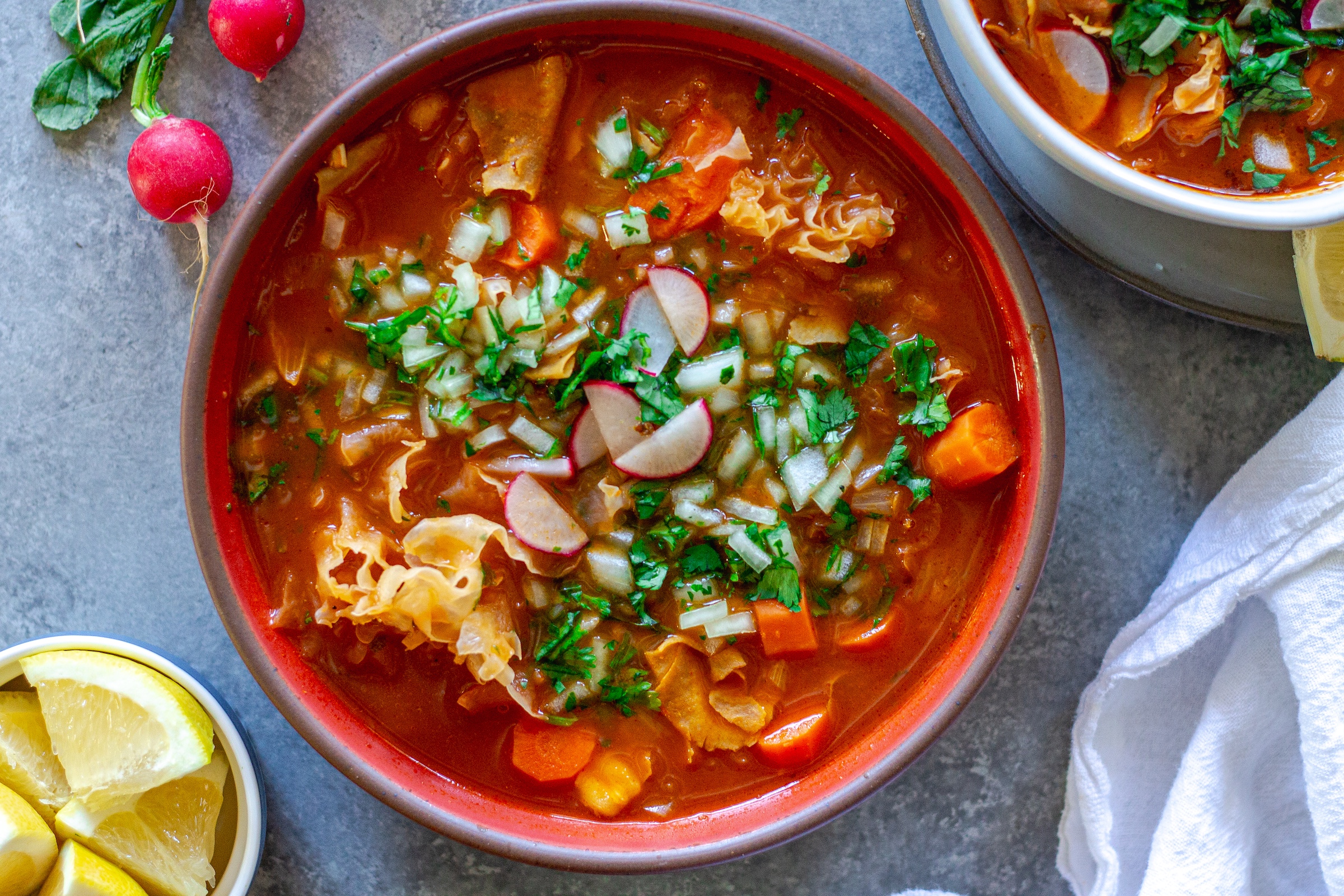 Bowl of vegan menudo with snow mushrooms, hominy, and red chile broth
