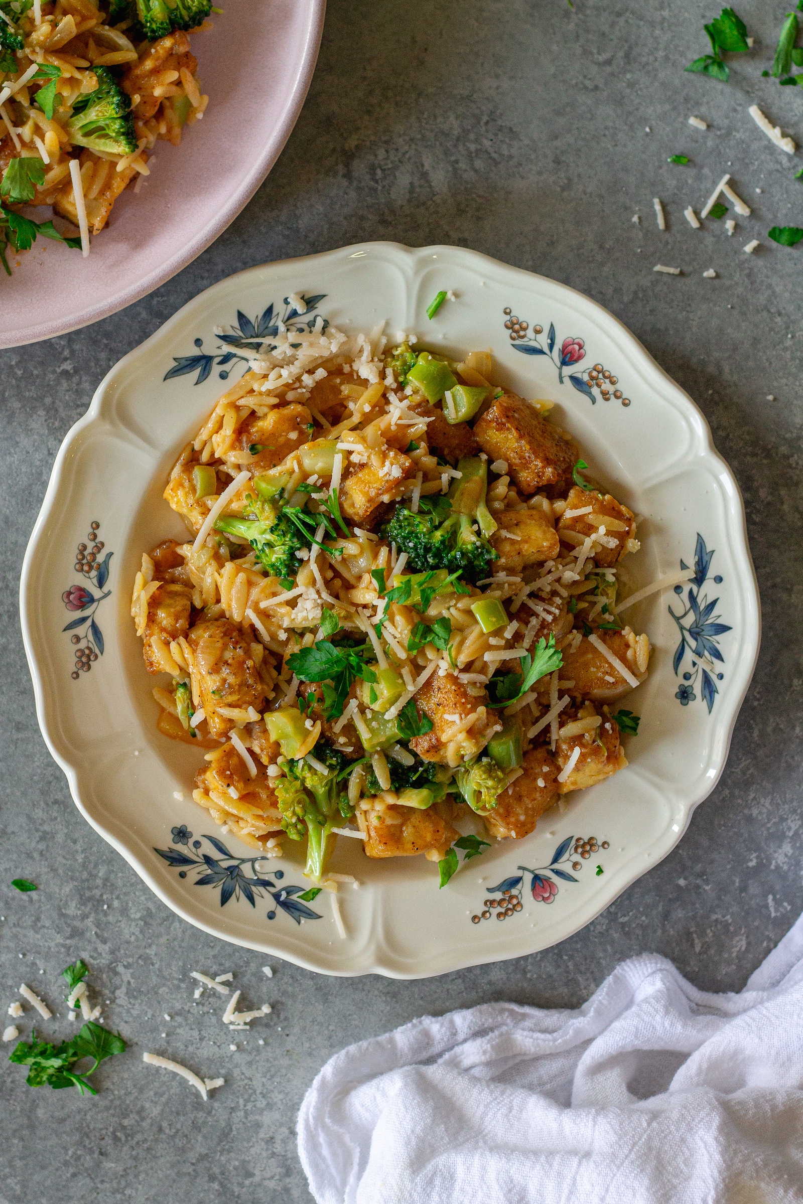 image of creamy One pan Cajun-inspired tofu Alfredo and orzo served on a plate and garnished with vegan parmesan and parsley