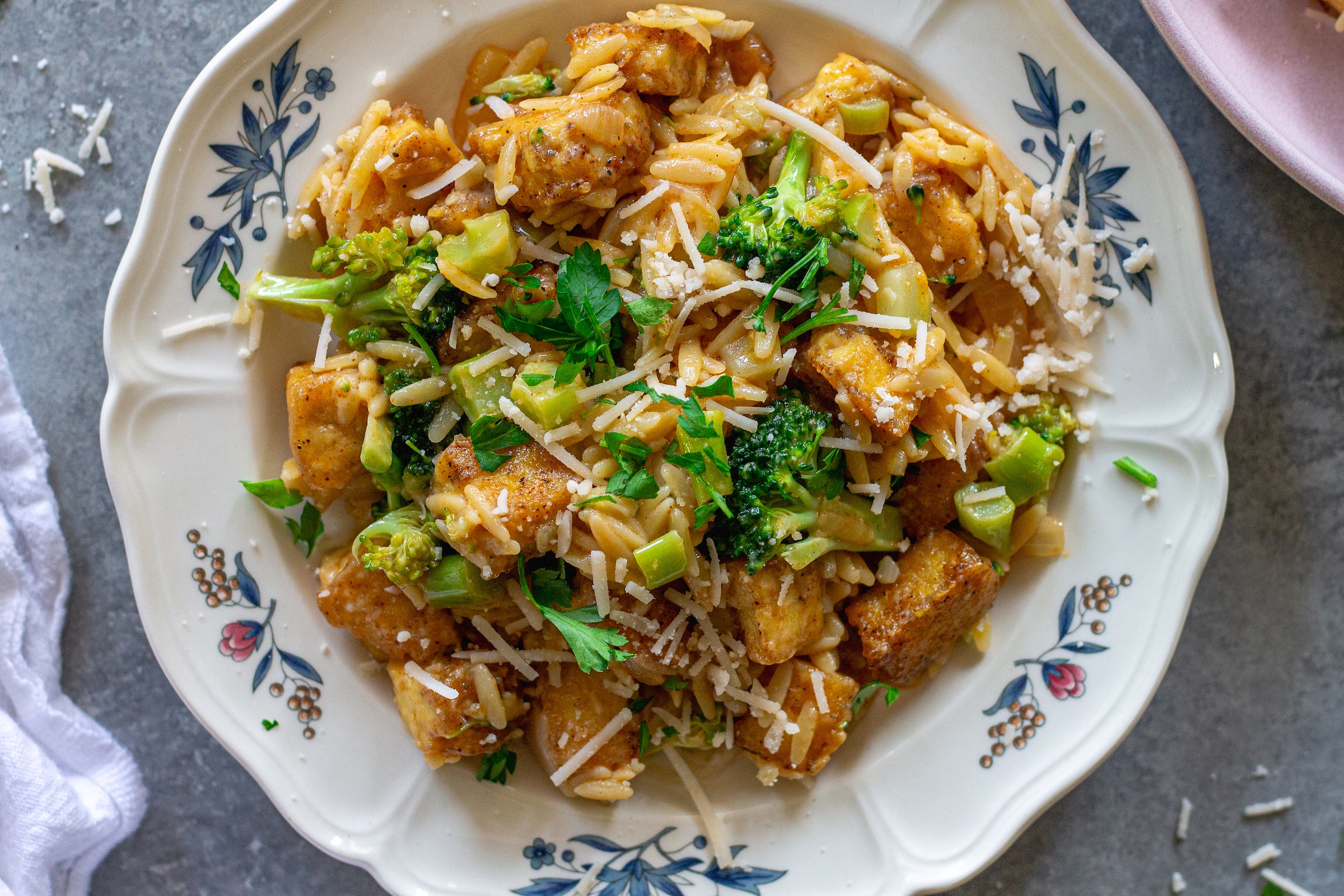 image of creamy One pan Cajun-inspired tofu Alfredo and orzo served on a plate and garnished with vegan parmesan and parsley