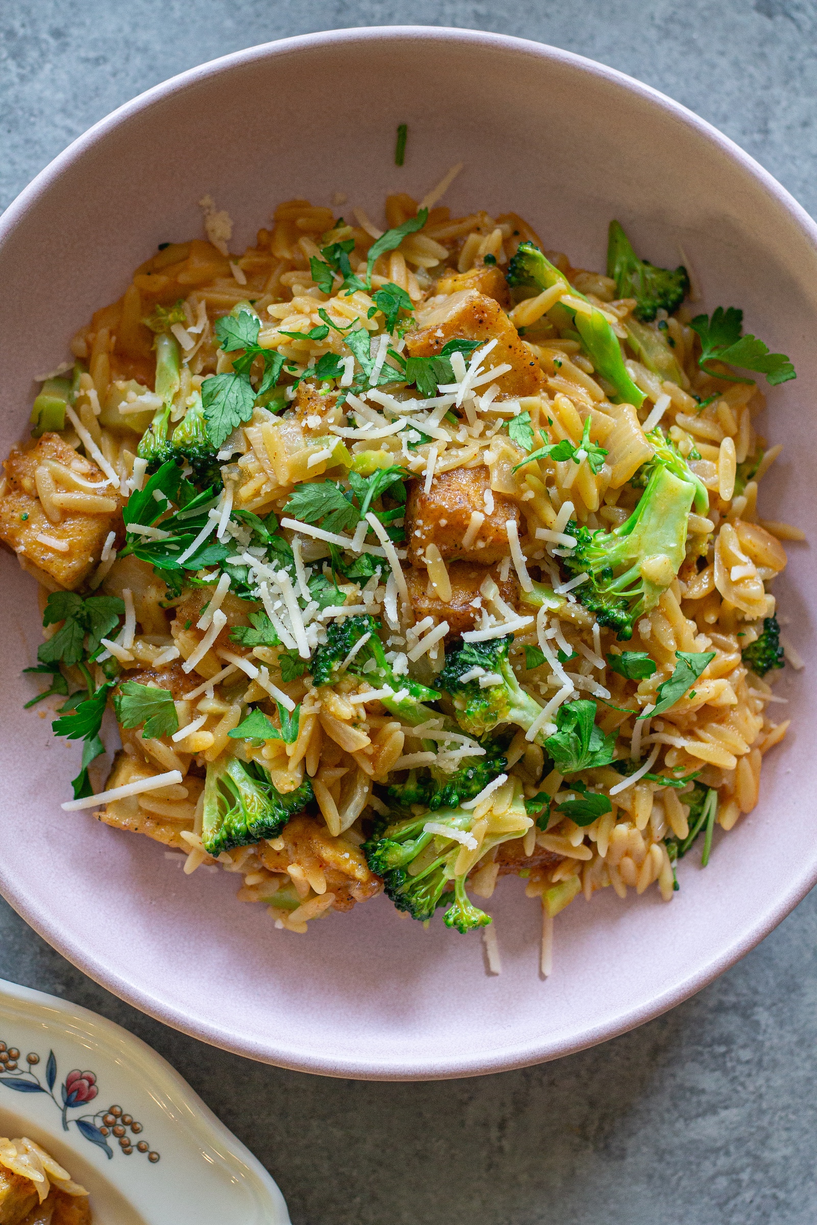 image of creamy One pan Cajun-inspired tofu Alfredo and orzo served on a plate and garnished with vegan parmesan and parsley
