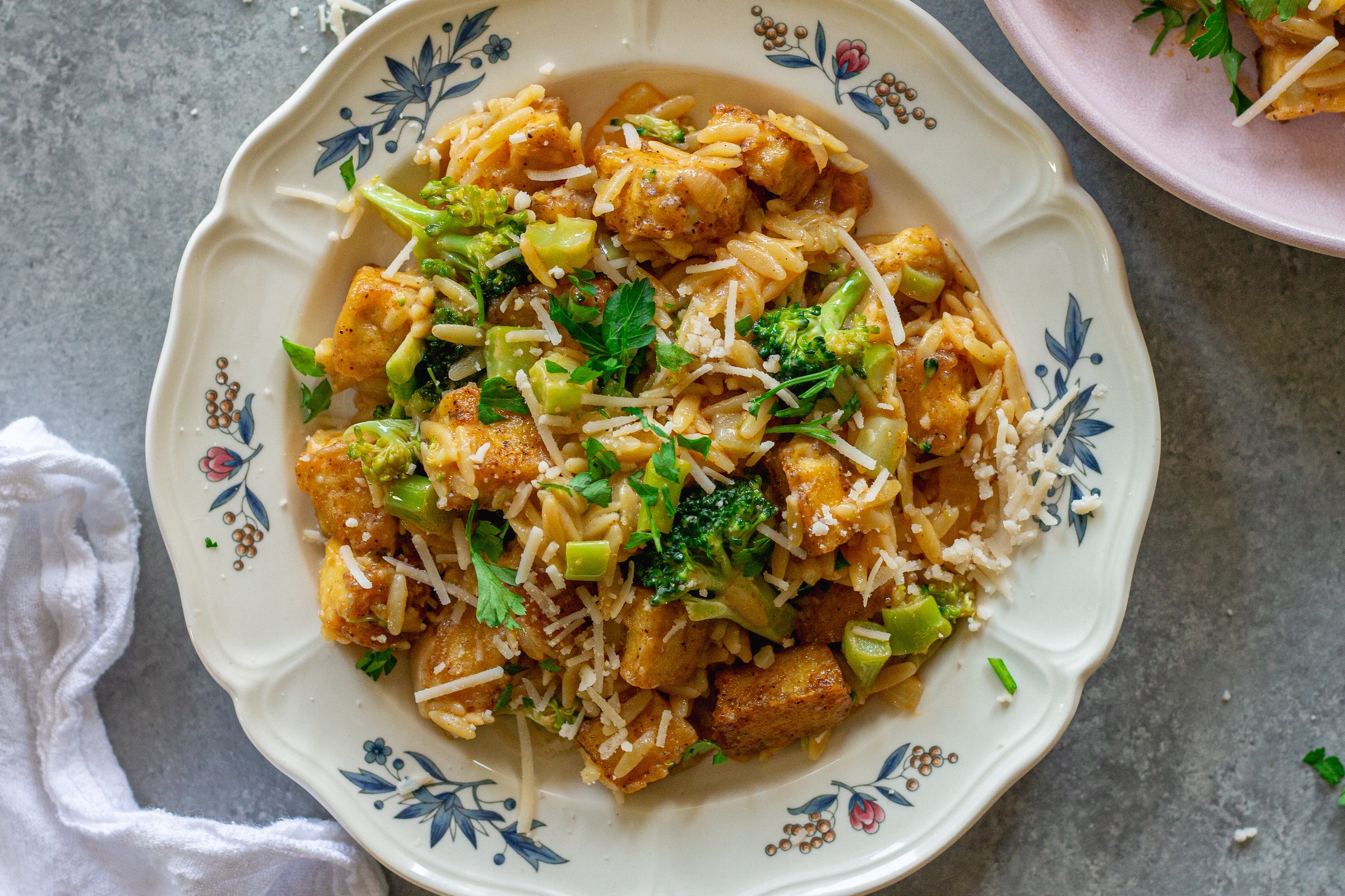 image of creamy One pan Cajun-inspired tofu Alfredo and orzo served on a plate and garnished with vegan parmesan and parsley