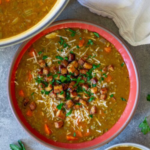 Bowl of creamy vegan split‑pea soup garnished with crispy tofu “bacon” and fresh parsley.