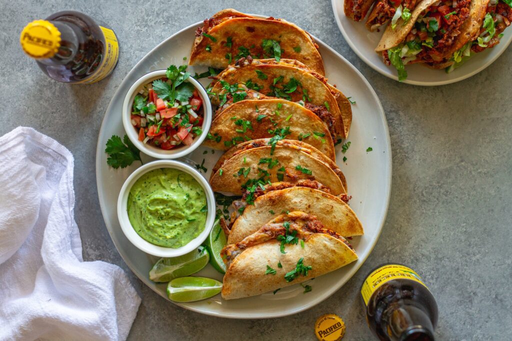 crispy baked chipotle tofu tacos garnished with cilantro and served with a side of avocado cream sauce and pico de Gallo.