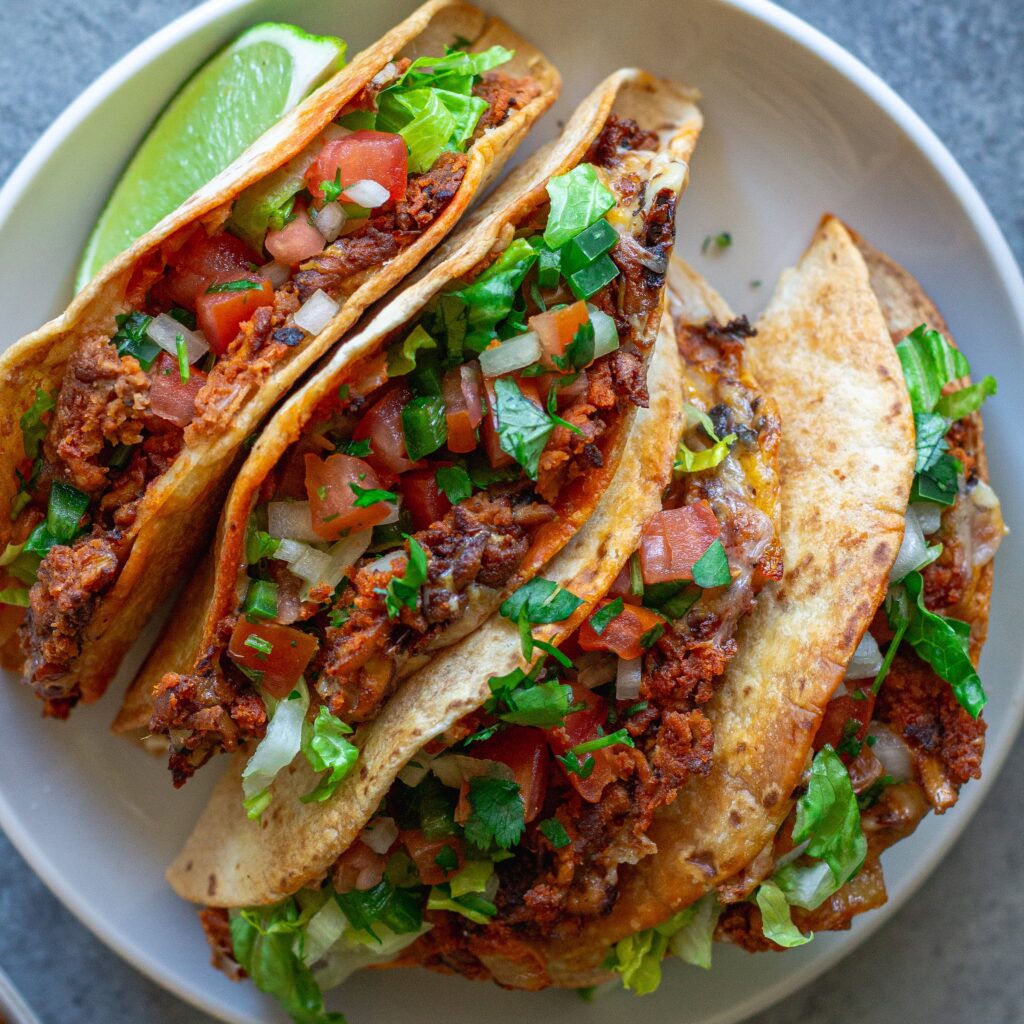 crispy baked chipotle tofu tacos garnished with cilantro and served with a side of avocado cream sauce and pico de Gallo.