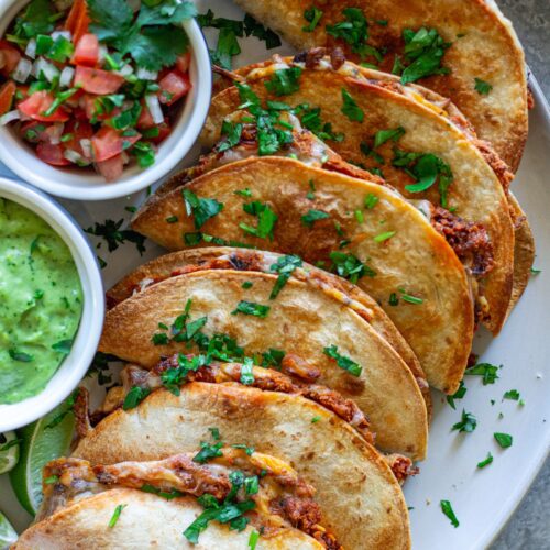 crispy baked chipotle tofu tacos garnished with cilantro and served with a side of avocado cream sauce and pico de Gallo.
