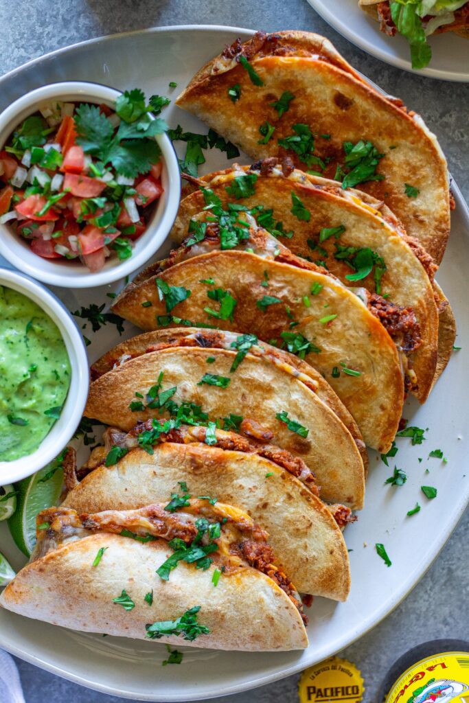 crispy baked chipotle tofu tacos garnished with cilantro and served with a side of avocado cream sauce and pico de Gallo.