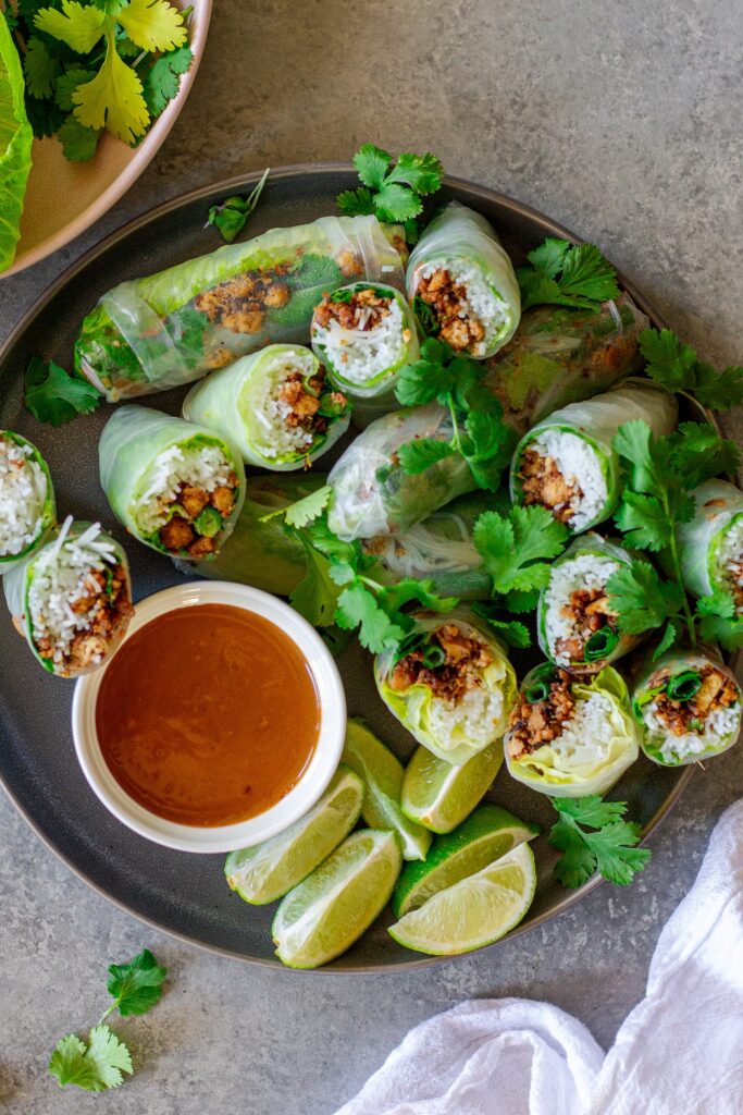 Fresh lemongrass tofu rice paper rolls cut in half with peanut sauce on the side