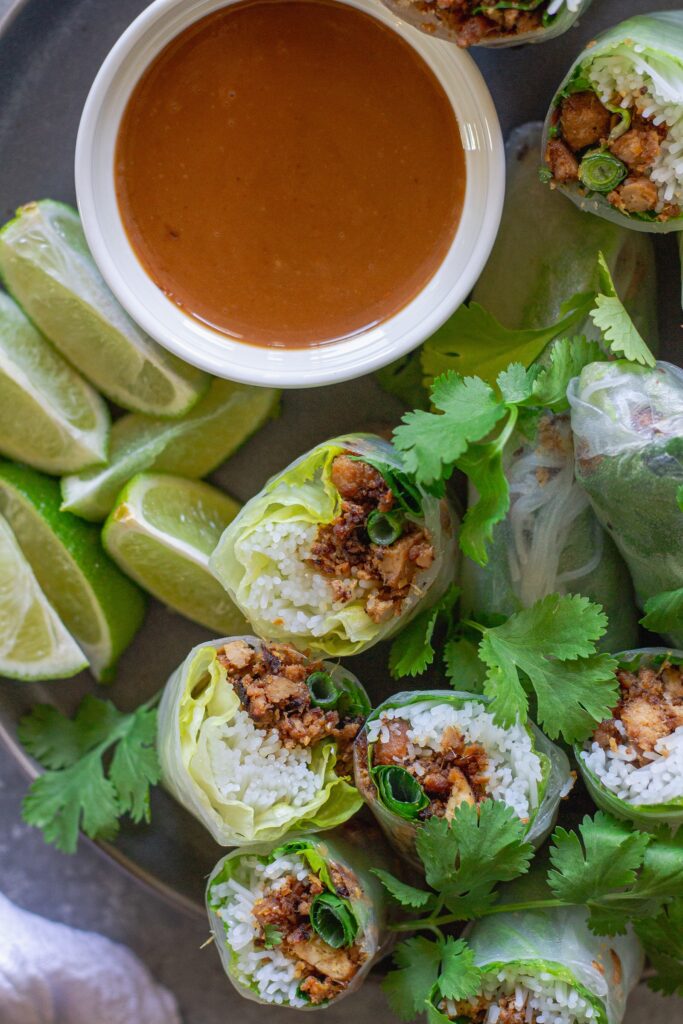 Fresh lemongrass tofu rice paper rolls cut in half with peanut sauce on the side